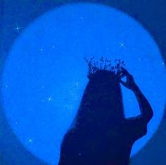 the silhouette of a woman wearing a tiara against a blue background with stars in the sky