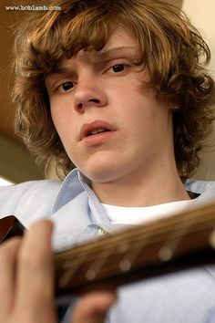 a young man holding a guitar in his hands