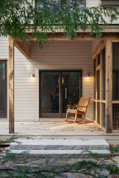 a wooden bench sitting on top of a patio next to a building with sliding glass doors