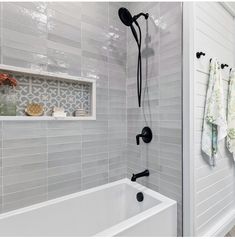 a white bath tub sitting under a window next to a shower head and hand held faucet