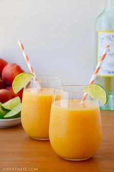 two glasses filled with orange juice next to fruit