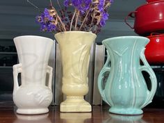 three different colored vases sitting on top of a table