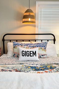 a bed with a pillow that says gigem on it and a lamp above it