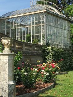 a glass house surrounded by flowers and greenery