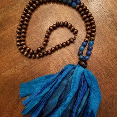 Beautiful Long Handmade Bead Necklace With High Quality Heavy Wood Beads And Glass Blue Beads. The Necklace Comes Together To A Large Black Glitter Bead And A Beautiful Blue Handmade Silk Tassel. Has A Clasp To Put Necklace On With Ease. Necklace Measures 19" Long And Tassel Is 6". Makes A Great Gift! Festival Beaded Necklaces With Tassels And Round Beads, Turquoise Beaded Necklace With Tassels And Round Beads, Turquoise Beaded Necklace With Tassels, Bohemian Beaded Necklaces With Tassels, Bohemian Brown Beaded Necklaces With 8mm Beads, Bohemian Brown Beaded Necklace With 8mm Beads, Bohemian Tassel Necklace With Round Beads For Beach, Blue Bohemian Beaded Necklace For Festivals, Adjustable Bohemian Tassel Necklace With Beaded Fringe