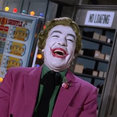 a man in a pink suit and green tie with his mouth open wearing a joker mask