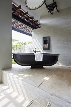 a bath tub sitting on top of a cement floor next to a clock mounted above it