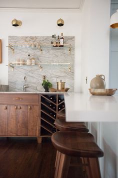 a kitchen with marble counter tops and wooden stools next to a wine rack on the wall