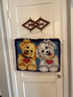 a door hanger with two dogs on it's side hanging from the front door