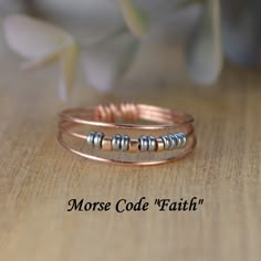 two rings with beads on them sitting on top of a wooden table next to flowers