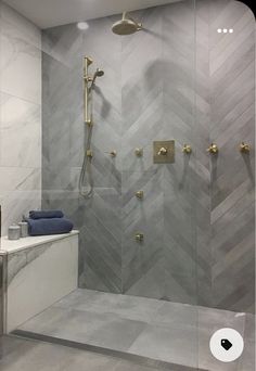 a walk in shower sitting next to a white bath tub and tiled walls with gold fixtures