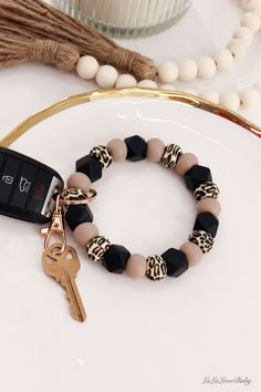 a black and white bracelet with a gold key on it next to a beaded necklace