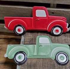 two red and green toy trucks sitting on top of wooden boards