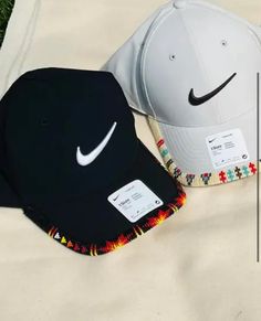 two hats sitting on top of a bed next to each other, one black and one white