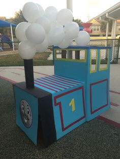 a cardboard train with balloons attached to it