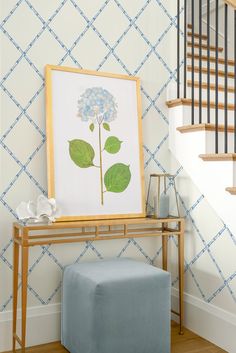 a blue ottoman sits in front of a painting on the wall next to a stair case