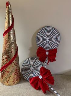 two lollipops are sitting next to each other near a christmas tree with red ribbon