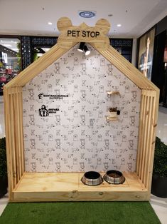 a dog house made out of wood with two bowls on the ground in front of it