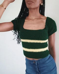 a woman with long black hair wearing a green crop top