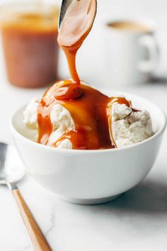 caramel sauce being drizzled over ice cream in a white bowl with spoon