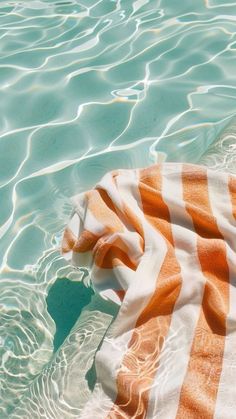 an orange and white towel laying on top of a body of water