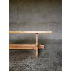 a wooden bench sitting on top of a cement floor next to a wall and concrete walls