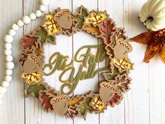 a wreath with the word fall on it next to some pumpkins and other decorations