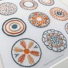 embroidery designs on a white cloth with orange and black accents, arranged in different circles