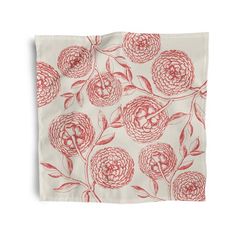 a red and white floral print napkin on a white background with an orange flower in the middle