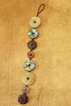 a necklace made out of buttons and other items on top of a brown cloth covered surface