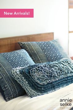 a bed topped with pillows and blankets next to a window