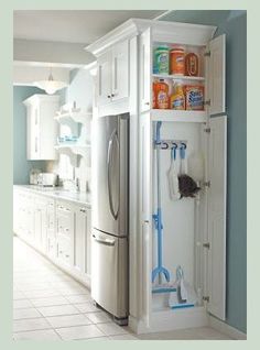 a kitchen with blue walls and white cabinets, including a refrigerator freezer that has cleaning supplies in it