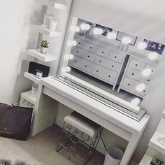 a white vanity with lights on it and a black bag sitting in front of it