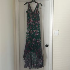 a dress hanging on a door handle in front of a white door with a black and pink floral print