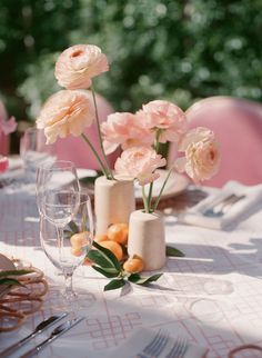 the table is set with pink flowers in vases