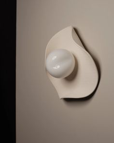 a white object is mounted on the wall with a round knob in it's center