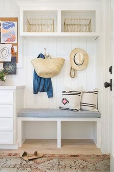 a white bench sitting under a shelf filled with hats and other items on top of it