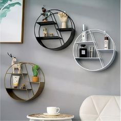 two round shelves on the wall above a white chair and table with a coffee cup