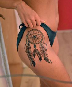 a woman's leg with a tattoo on it that has a small dream catcher