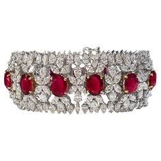 One-of-a-kind, AGL-certified Burmese ruby and diamond wide tennis bracelet crafted in 18-karat white and 18-karat yellow gold. The 13 oval-shaped Burma rubies are AGL-certified and measure in size from 10.00 x 7.70 x 3.16 mm to 8.32 x 6.82 x 4.23mm. Each ruby slightly increases in size, making the center ruby the largest. The rubies are set in 18-karat yellow gold, which accentuates their bold red color.  The design, though intricate, is far from delicate. Diamond clusters encircle the rubies wi Luxury Ruby Bracelet Elegant Style, Luxury Ruby Bracelet For Anniversary, Burmese Ruby, Diamond Jewelry Set, Diamond Pendants Designs, Bracelet Tennis, Ruby Bracelet, Diamond Pendants, Wide Bracelet