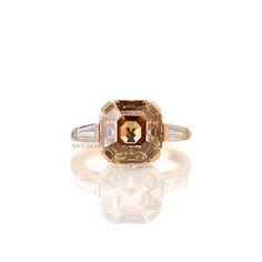 an orange and white diamond ring with three baguets on the side, set in 18k yellow gold