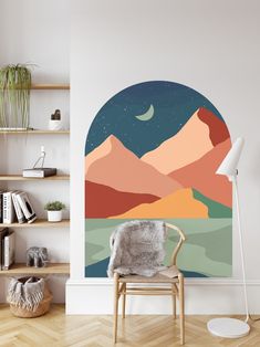 a living room with a chair, book shelf and wall mural in the shape of mountains