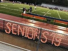 an overhead view of a football field with the words seniors spelled in neon orange letters