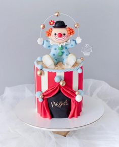 a birthday cake decorated with a clown on top of a red and white striped box