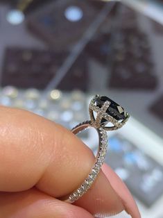 someone is holding a ring with a black diamond in it's center and white diamonds around the band