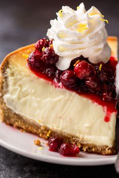 a piece of cheesecake with whipped cream and cherries on top sits on a plate