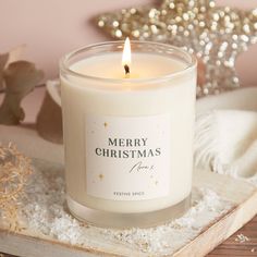 a white candle sitting on top of a wooden tray next to a christmas tree ornament