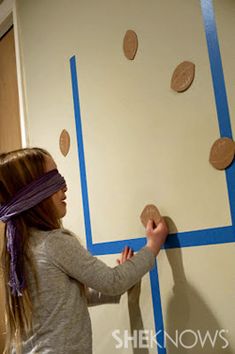 a girl is painting the wall with blue tape and some circles on it in an empty room