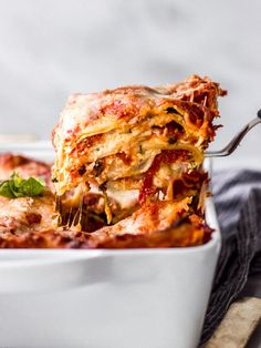 a close up of a casserole in a white dish with a fork sticking out of it