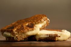 two grilled cheese sandwiches sitting on top of a wooden cutting board